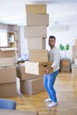 Young handsome man moving to a new apartment, holding a pile of cardboard boxes, happy for new home Royalty Free Stock Photo