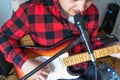 Young handsome man, musician, singer studying,practicing to play electric guitar at home,singing songs into microphone.Hobby, Royalty Free Stock Photo