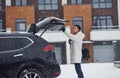 Young handsome man outdoors near his modern black car at winter time Royalty Free Stock Photo