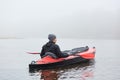 Young handsome man paddling canoe on cloudy day, canoeing on foggy day, back view of extreme sportsman enjoying water sport in Royalty Free Stock Photo