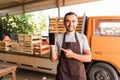 Young handsome man point on the phone with copyspace in front collect tomatoes boxes at greenhouse. Online phone sales of tomato o Royalty Free Stock Photo