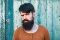 Young handsome man, portrait face of serious bearded hipster on wooden background. Royalty Free Stock Photo