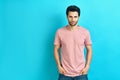 Young handsome man portrait wearing pink t-shirt looking at camera on blue background Royalty Free Stock Photo