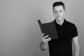 Young handsome man reading book against gray background Royalty Free Stock Photo