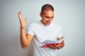 Young handsome man reading red book over white isolated background very happy and excited, winner expression celebrating victory Royalty Free Stock Photo