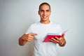 Young handsome man reading red book over white isolated background very happy pointing with hand and finger Royalty Free Stock Photo