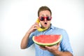 Young handsome man in red eyeglasses with watermelon holding banana like a phone on isolated white background Royalty Free Stock Photo