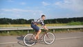 Young handsome man riding at vintage bicycle in the country road. Sporty guy cycling at the track. Male cyclist riding Royalty Free Stock Photo