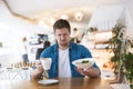 Young handsome man seems to be unhappy with with quality of salad and taste of coffee during lunch at the cafe, complaints and