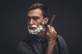 Young handsome man with shaving cream on his face, grooming his beard Royalty Free Stock Photo