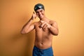 Young handsome man shirtless wearing swimsuit and swim cap over isolated yellow background smiling doing talking on the telephone Royalty Free Stock Photo
