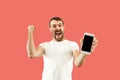 Young handsome man showing smartphone screen isolated on coral background in shock with a surprise face Royalty Free Stock Photo