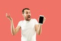 Young handsome man showing smartphone screen isolated on coral background in shock with a surprise face Royalty Free Stock Photo