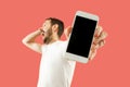 Young handsome man showing smartphone screen isolated on coral background in shock with a surprise face Royalty Free Stock Photo