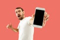 Young handsome man showing smartphone screen isolated on coral background in shock with a surprise face Royalty Free Stock Photo