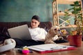 Young handsome man sitting and working at home with his cute dog. Cozy office workplace, remote work, online learning Royalty Free Stock Photo