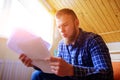 Young handsome man sitting on the couch and watches a working paper Royalty Free Stock Photo