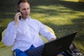 Handsome Man Sitting On The Grass In The City Working With A Laptop Royalty Free Stock Photo