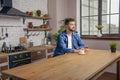 Young handsome man is sitting at his kitchen in the morning having his coffee and an apple juice and thinking Royalty Free Stock Photo