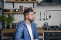 Young handsome man is sitting at the kitchen in the morning looking at the window thinking Royalty Free Stock Photo