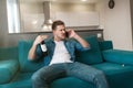 Young handsome man sitting on the sofa with a bottle of wine having irritating conversation on his smartphone in the cozy living