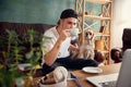 Young handsome man sitting on sofa at home with his cute dog. Cozy office workplace, remote work, online, e-learning Royalty Free Stock Photo