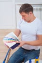 a young handsome man sitting on wooden floor holding color palette and looking on it Royalty Free Stock Photo