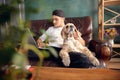 Young handsome man sitting and working at home with his cute dog. Cozy office workplace, remote work, online learning Royalty Free Stock Photo