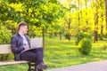 A young handsome man is sitting and working in the park with a laptop. The guy freelancer works outside and smile Royalty Free Stock Photo