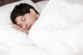 Young handsome man sleeping alone in white bed, soft linen Royalty Free Stock Photo