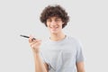 A young, handsome man smiles as he uses his smartphone, talking and listening with cellphone while looking into the camera with Royalty Free Stock Photo