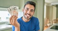 Young handsome man smiling happy holding england pounds banknotes at home