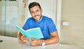 Young handsome man smiling happy reading book at home Royalty Free Stock Photo