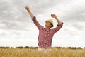 Young handsome happy man standing in wheat field spreading his arms up Royalty Free Stock Photo