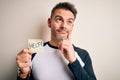 Young handsome man stressed holding reminder paper with help message serious face thinking about question, very confused idea Royalty Free Stock Photo