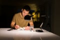 Young handsome man studying at home, reading a book at night Royalty Free Stock Photo