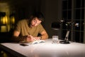 Young handsome man studying at home, reading a book at night Royalty Free Stock Photo