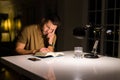 Young handsome man studying at home, reading a book at night Royalty Free Stock Photo