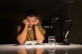 Young handsome man studying at home very bored and stressful reading a book at night Royalty Free Stock Photo