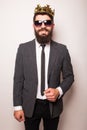 Young handsome man in sunglasses wearing suit and crown keeping hand on his jacket Royalty Free Stock Photo