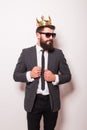 Young handsome man in sunglasses wearing suit and crown keeping hand on his jacket Royalty Free Stock Photo