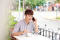 Young handsome man talking on the mobile phone while sitting in cafe outdoor Royalty Free Stock Photo