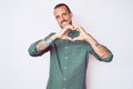 Young handsome man with tattoo wearing casual clothes smiling in love showing heart symbol and shape with hands