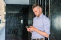 Young handsome man texting on cell phone outside office in New York City Royalty Free Stock Photo