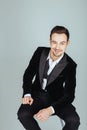 Young handsome man in a tuxedo, sitting and looking at the camera, bow tie undone Royalty Free Stock Photo