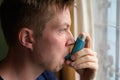 Young handsome man using asthma inhaler at home Royalty Free Stock Photo