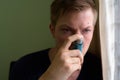 Young handsome man using asthma inhaler at home Royalty Free Stock Photo