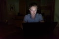 Young handsome man using laptop in the dark living room Royalty Free Stock Photo