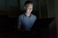 Young handsome man using laptop in the dark living room Royalty Free Stock Photo
