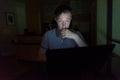 Young handsome man using laptop in the dark living room Royalty Free Stock Photo